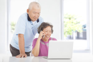 Senior couple using a laptop and a cell phone at home